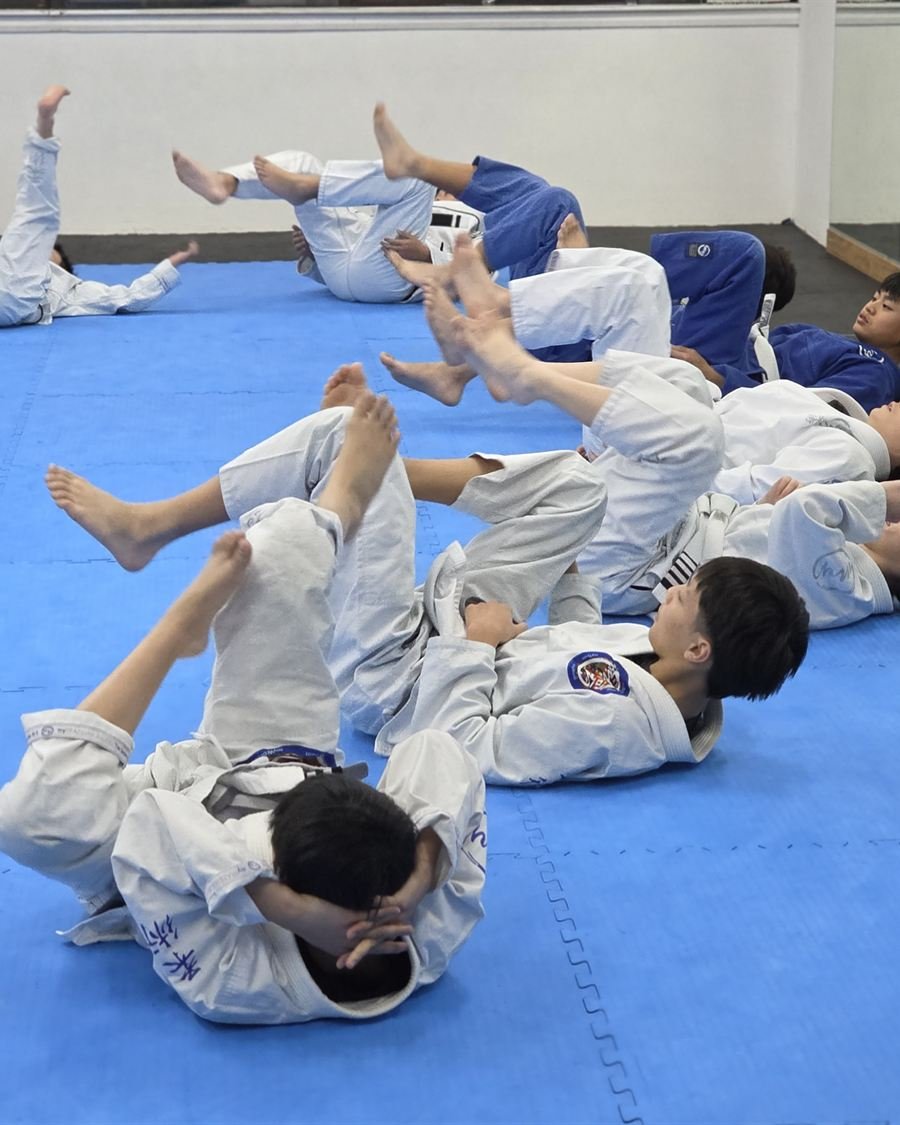 Students drilling in pairs across the mat