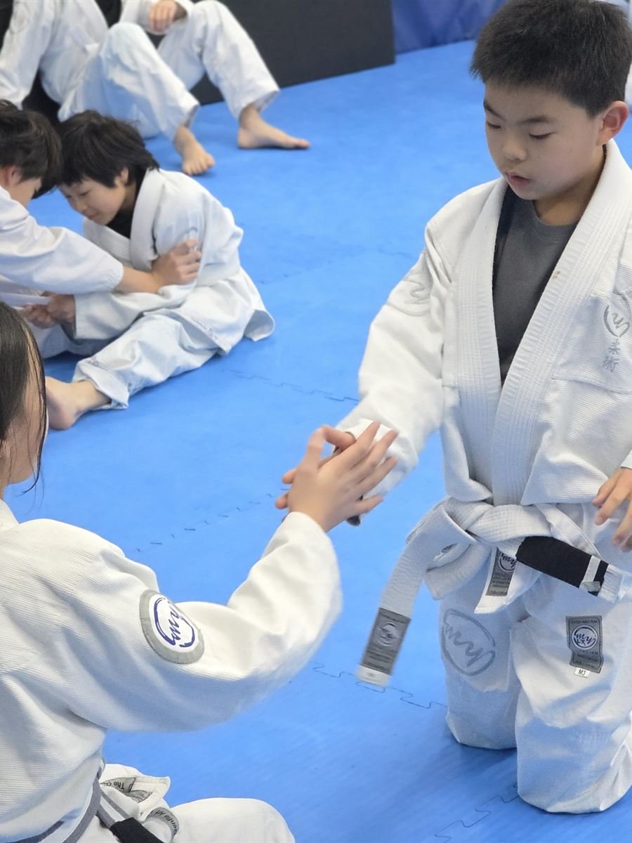 A coach guiding a young student through a technique