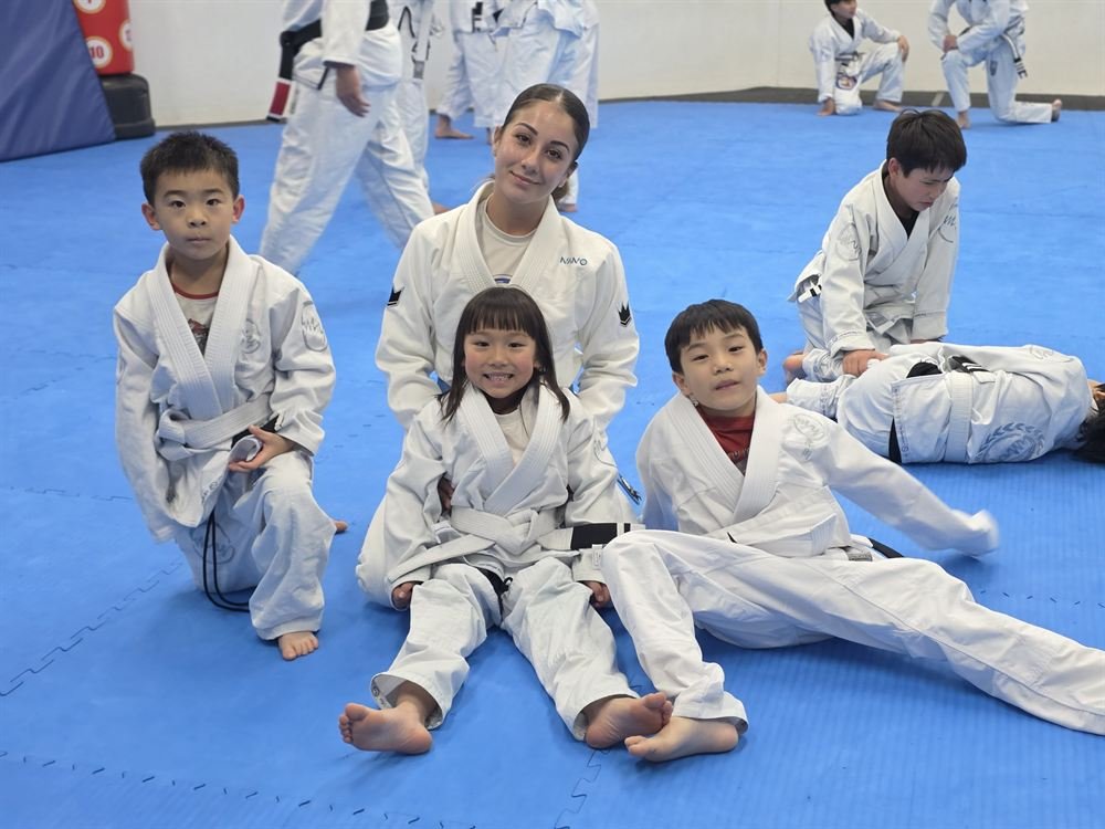 A coach sitting with young children during the kids class