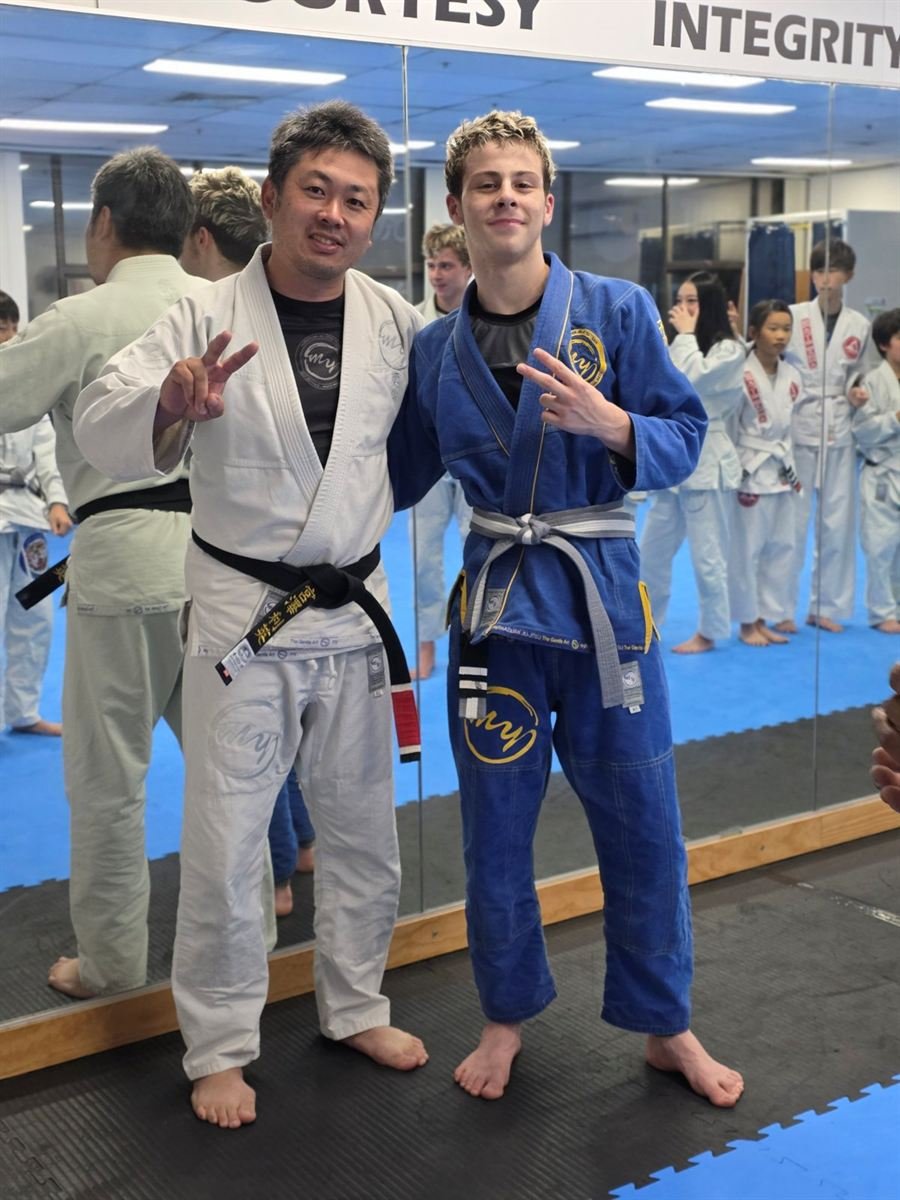 A student in a blue gi celebrating a promotion with Toshi