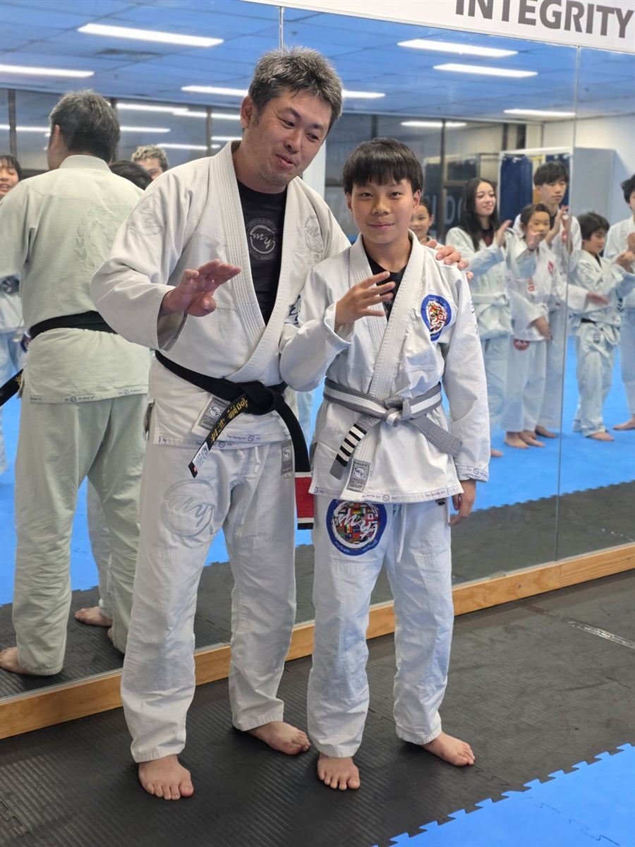 A young student celebrating a new belt with Toshi