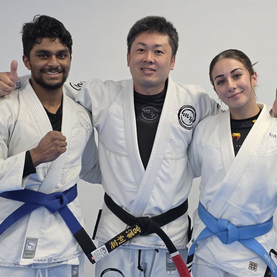 Three members in gis with their instructor after a session