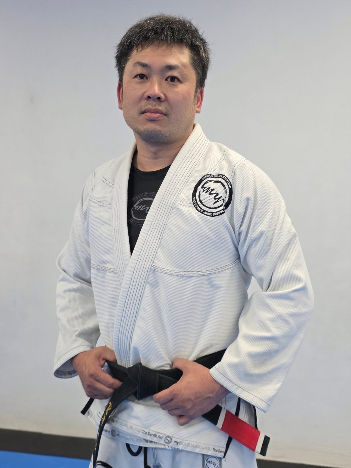 Head instructor Toshi Miyazawa in his gi and black belt, standing with a student